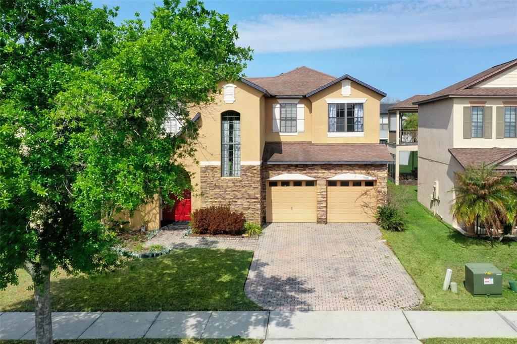 A two-story house with a tan stucco exterior, stone accents, and a two-car garage — 9708 OLD PATINA WAY, ORLANDO, FL