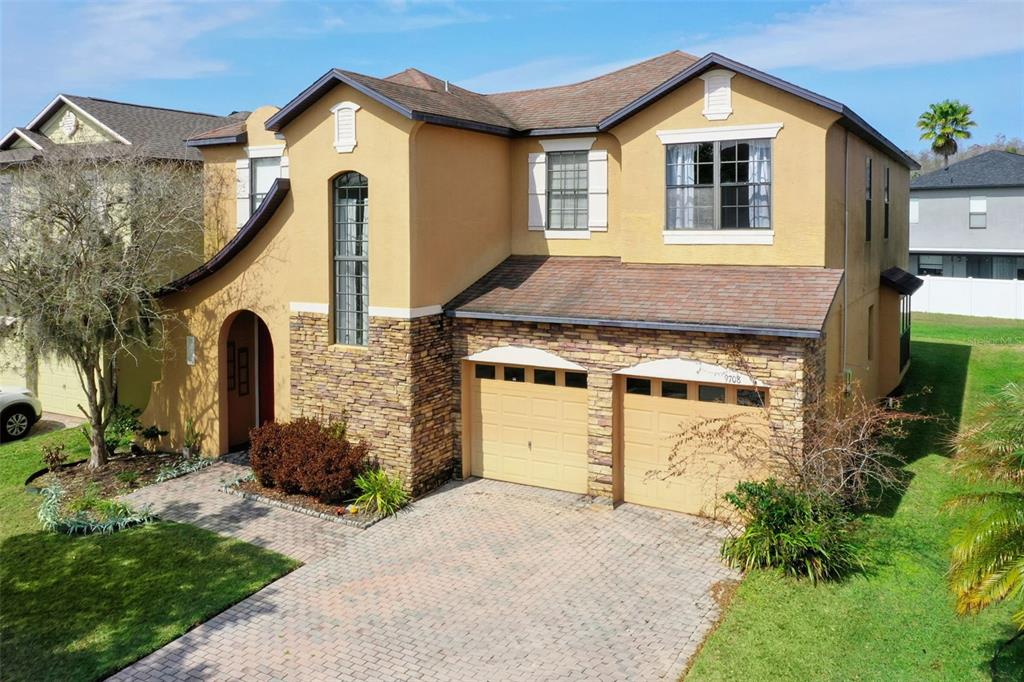 A two-story house with a tan stucco exterior, stone accents, and a two-car garage — 9708 OLD PATINA WAY, ORLANDO, FL