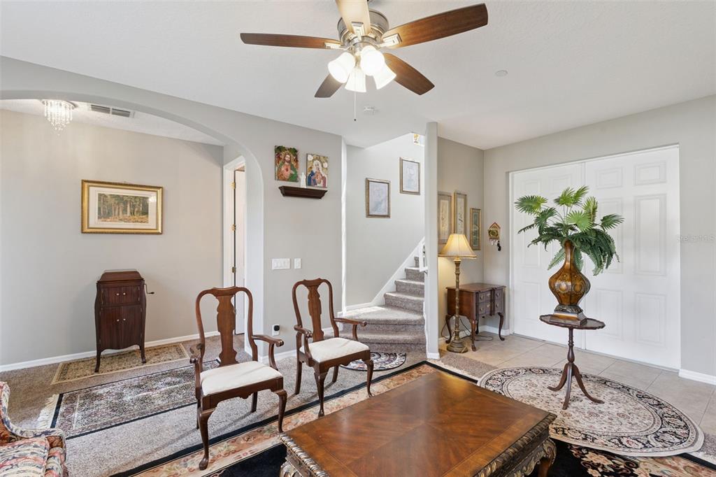 A living room features a ceiling fan, two wooden chairs, and a staircase — 9708 OLD PATINA WAY, ORLANDO, FL