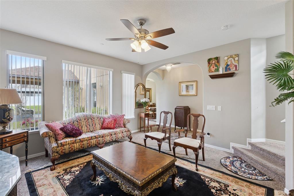 A living room features a patterned sofa, wooden coffee table, two chairs, and a ceiling fan — 9708 OLD PATINA WAY, ORLANDO, FL