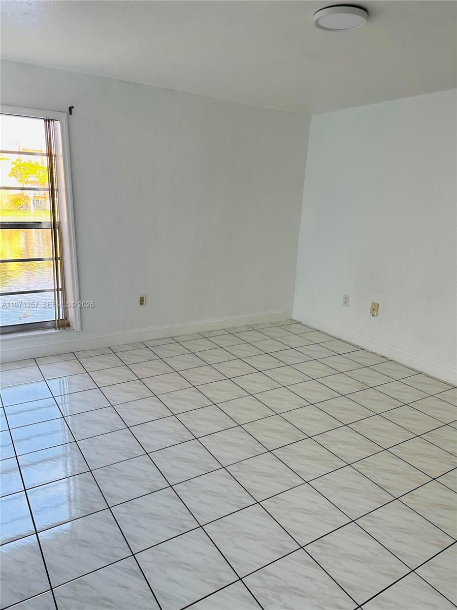 An empty room features white walls, light-colored tiled flooring, and a window overlooking water — 4705 NW 7th St # 7, Miami FL 33126, MIAMI, FL