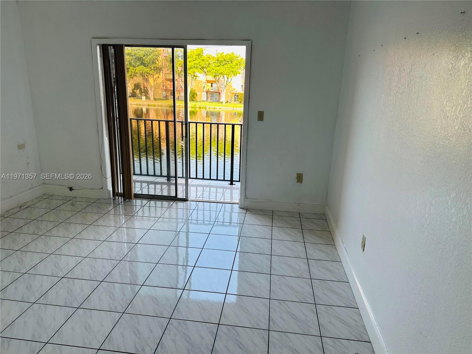 A room with white tile flooring and a sliding glass door opening to a balcony — 4705 NW 7th St # 7, Miami FL 33126, MIAMI, FL