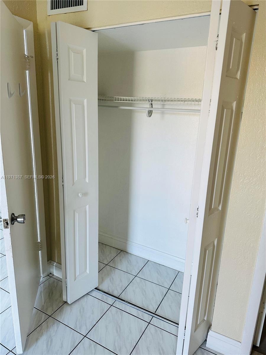 An open white closet with a wire shelf is set against a tiled floor — 4705 NW 7th St # 7, Miami FL 33126, MIAMI, FL
