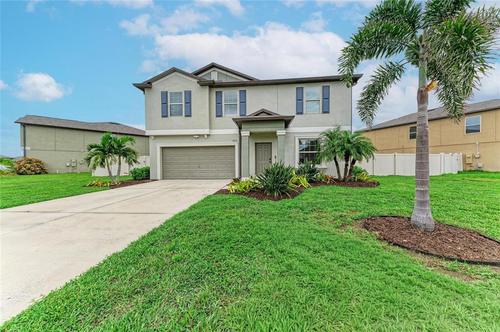 A two-story suburban house with a concrete driveway, attached garage, and a front yard — 5512 OLANO STREET, PALMETTO, FL
