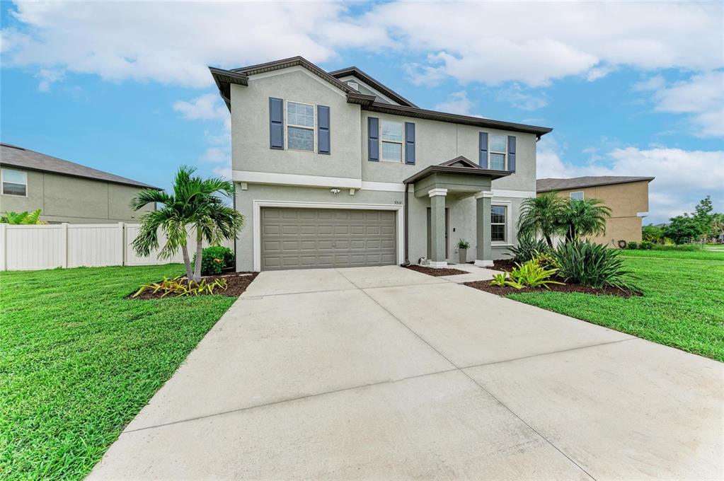 A two-story suburban house with a concrete driveway, garage, and front landscaping — 5512 OLANO STREET, PALMETTO, FL