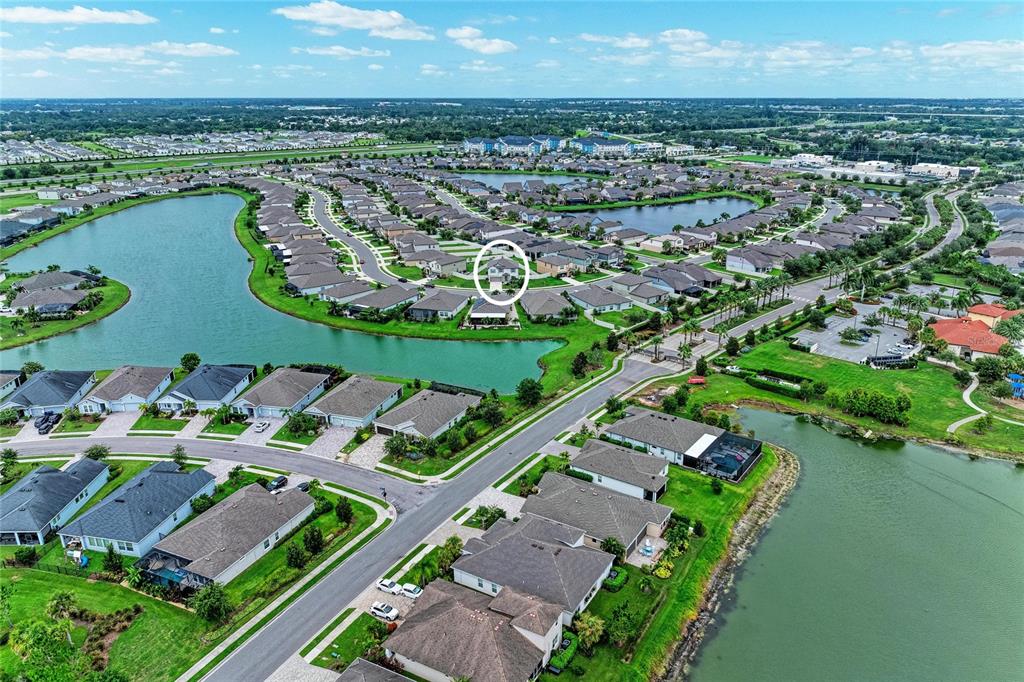 An aerial view shows a residential neighborhood with houses surrounding a lake — 5512 OLANO STREET, PALMETTO, FL