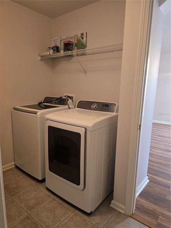 An empty room with wood-look flooring, a single window with blinds, and a hanging chandelier — 31125 HANNIGAN PLACE, WESLEY CHAPEL, FL