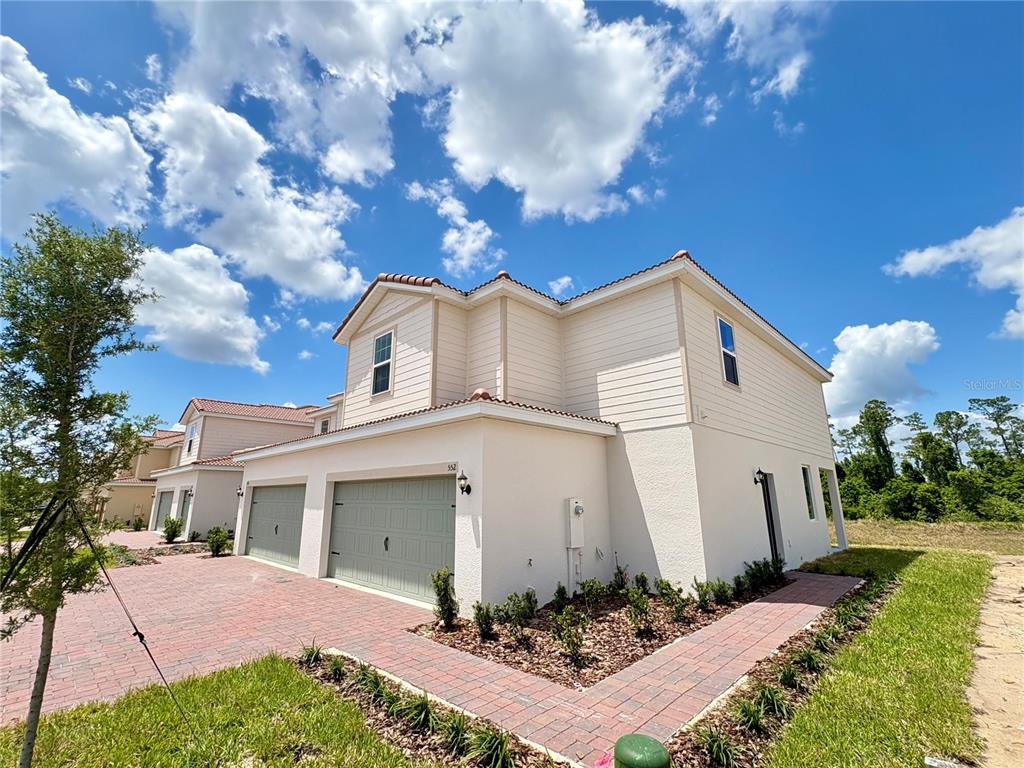 A two-story house with a two-car garage, light siding, and a brick paver driveway — 552 BAY LEAF DRIVE, POINCIANA, FL