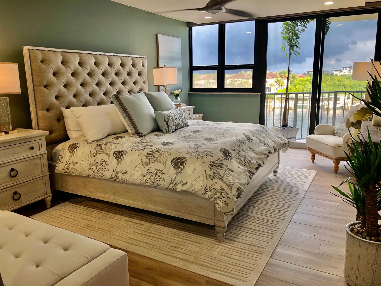 A bedroom features a tufted headboard, shell-patterned bedding, and a balcony overlooking the water — 899 Jeffery Street # 4150, Boca Raton FL 33487, BOCA RATON, FL