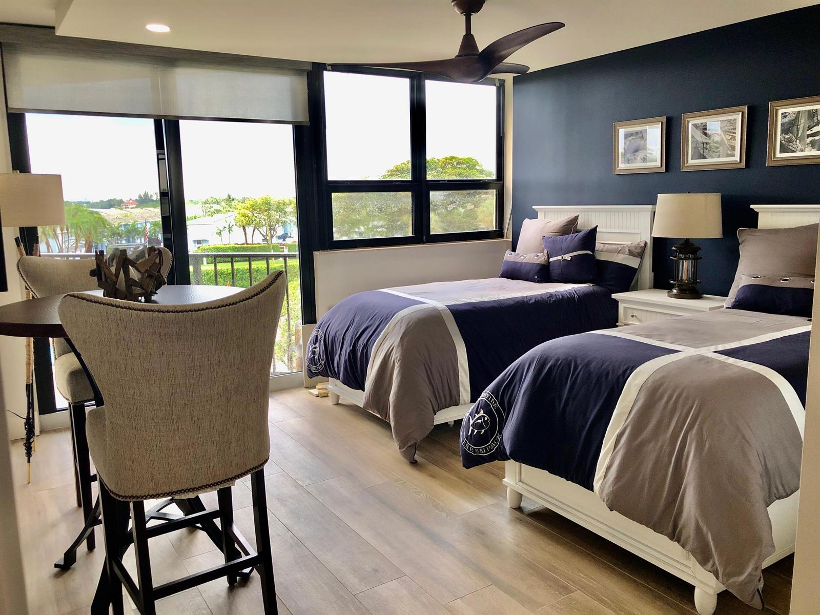 A bedroom with two twin beds, a small dining area, and a view of greenery — 899 Jeffery Street # 4150, Boca Raton FL 33487, BOCA RATON, FL