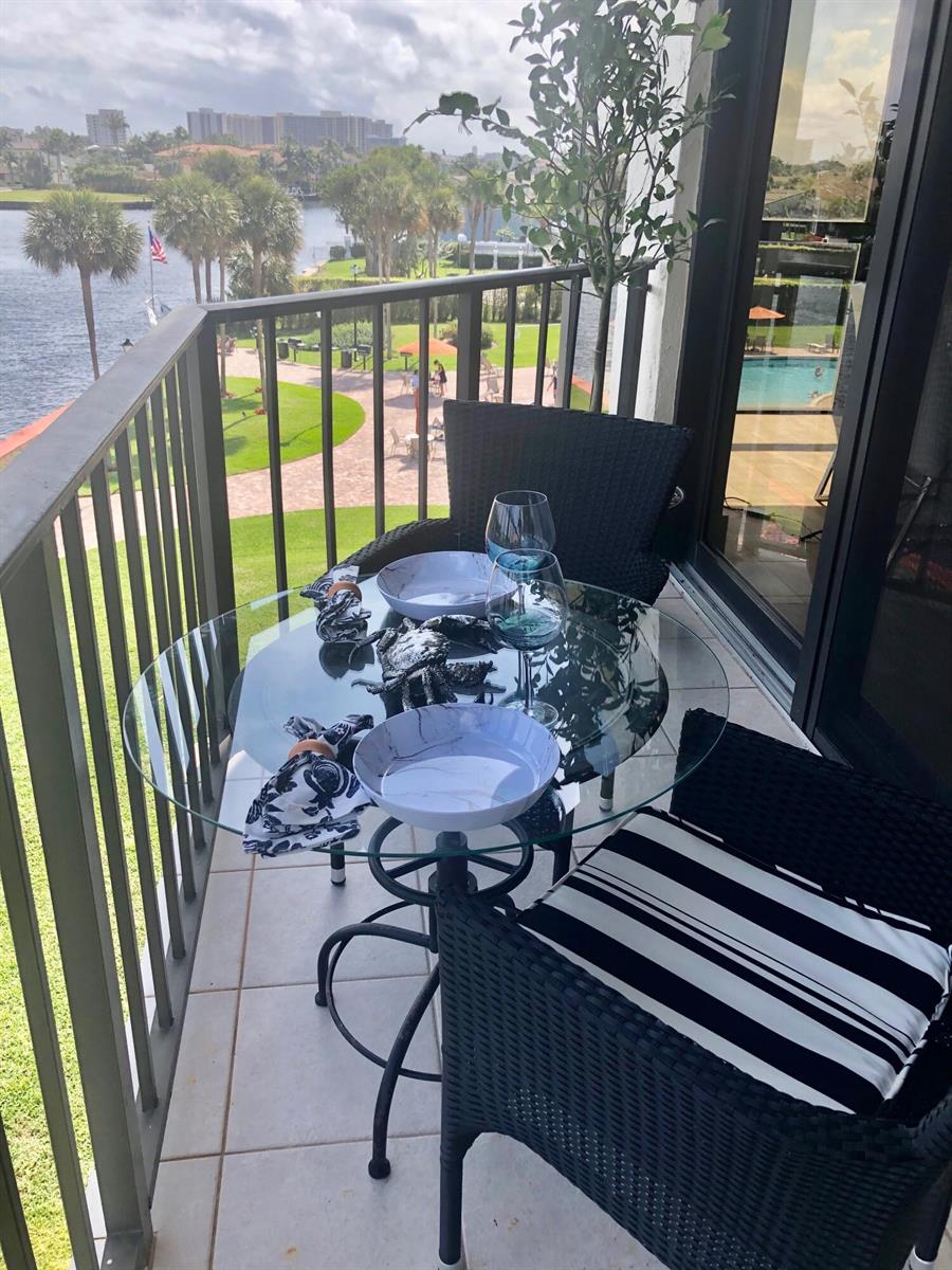 A balcony features a glass-topped bistro table with two chairs overlooking a waterfront view — 899 Jeffery Street # 4150, Boca Raton FL 33487, BOCA RATON, FL