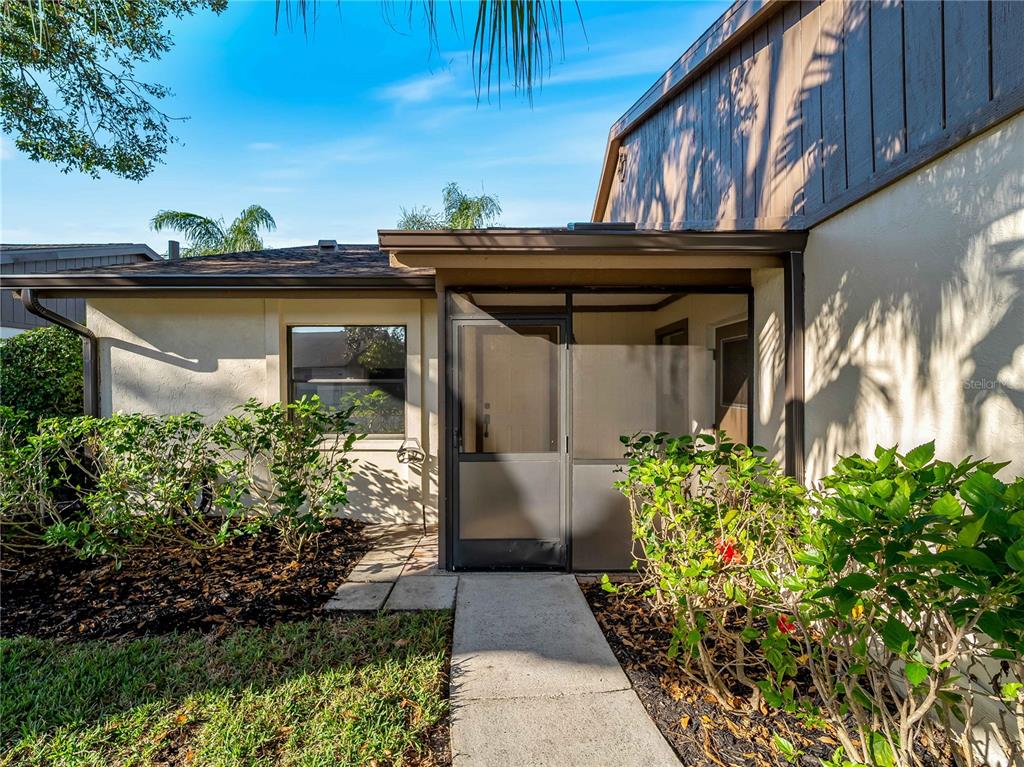 A concrete walkway leads to the screened front entryway of a single-story home — 365 OAK HILL WAY UNIT 32, SARASOTA, FL