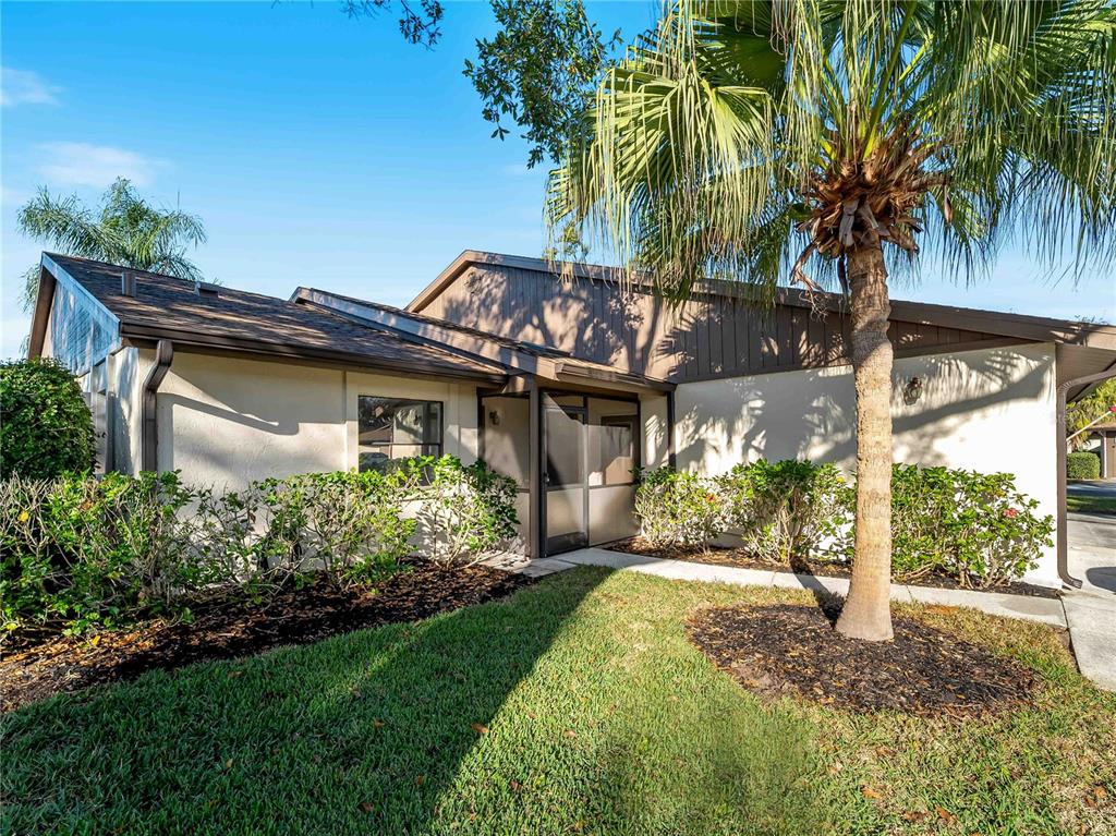 A single-story house with a screened entryway, brown trim, and a palm tree in front — 365 OAK HILL WAY UNIT 32, SARASOTA, FL