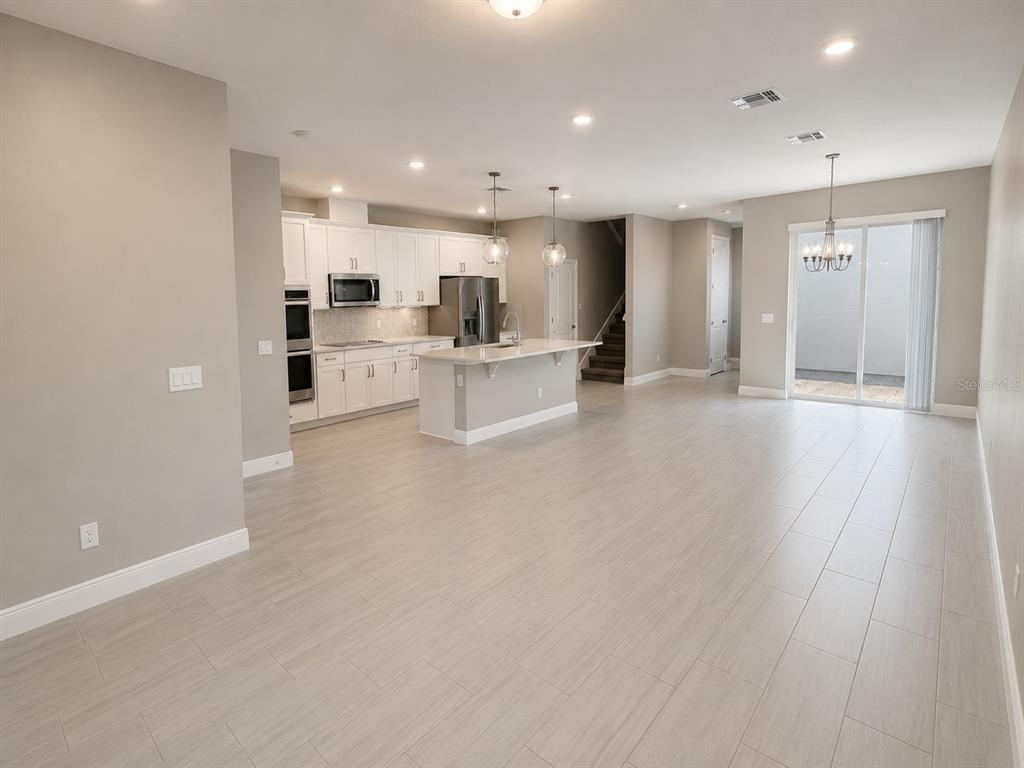 An open-concept kitchen and living area features white cabinetry, a center island, and light flooring — 7248 CARRICKBEND LANE, ORLANDO, FL