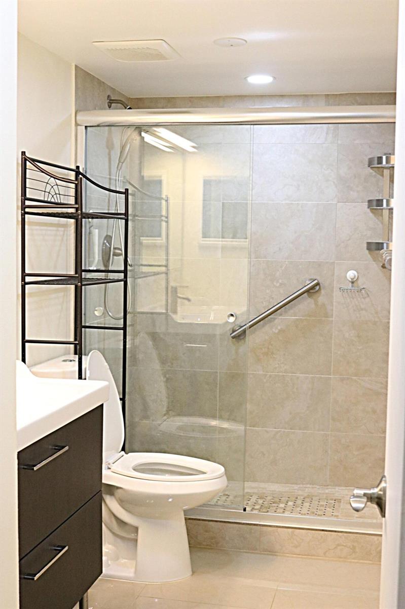 A bathroom featuring a glass-enclosed walk-in shower, a toilet, and a dark wood vanity — 230 NE 26th Avenue # 1070, Boynton Beach FL 33435, BOYNTON BEACH, FL
