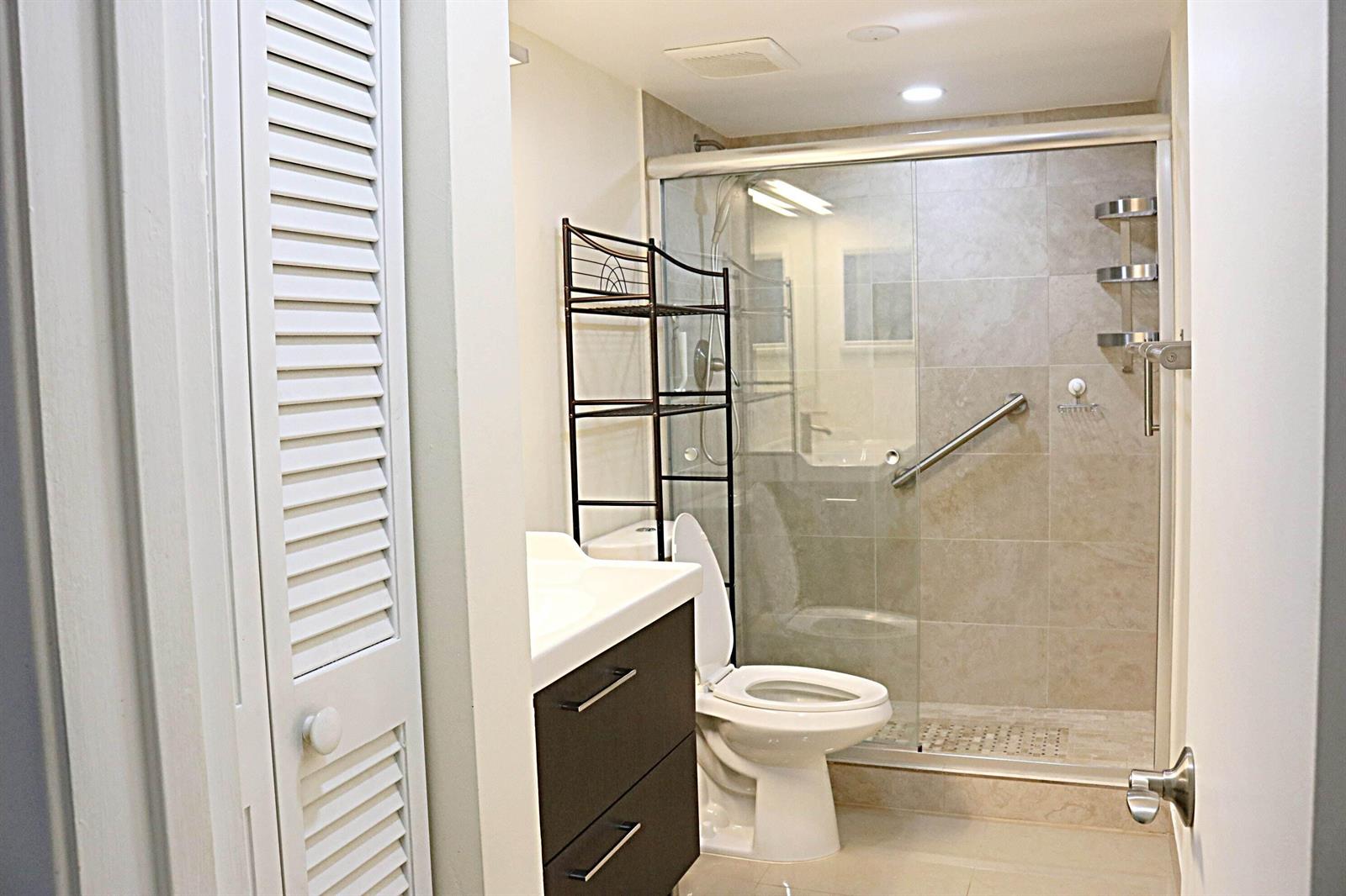 A bathroom features a vanity, a toilet, and a walk-in shower with glass sliding doors — 230 NE 26th Avenue # 1070, Boynton Beach FL 33435, BOYNTON BEACH, FL