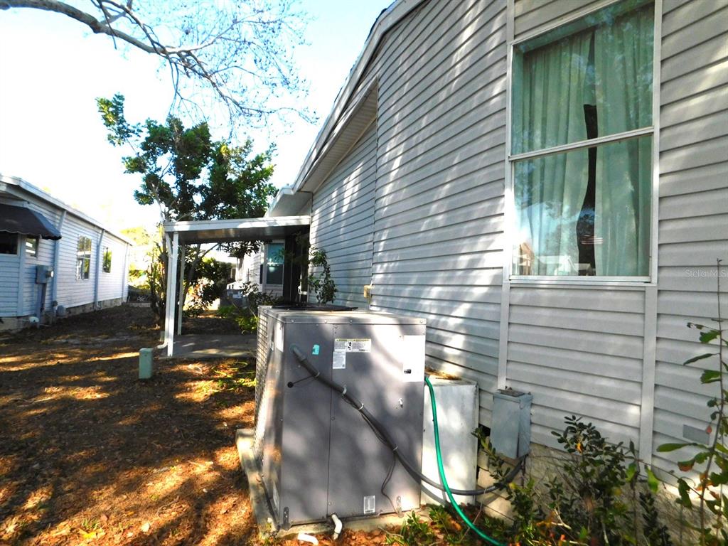 An exterior view shows a grey siding home with an HVAC unit and carport — 1001 STARKEY ROAD UNIT 639, LARGO, FL
