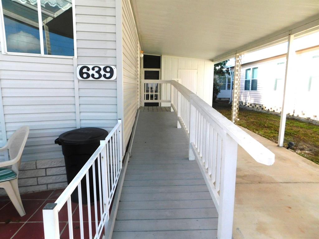 A wooden wheelchair ramp with white railings leads to the entrance of a mobile home — 1001 STARKEY ROAD UNIT 639, LARGO, FL