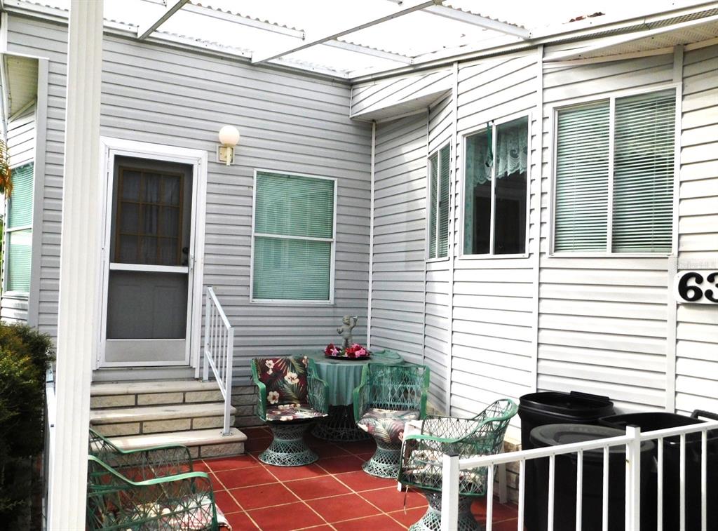 A covered patio with red tile flooring, outdoor furniture, and light gray vinyl siding — 1001 STARKEY ROAD UNIT 639, LARGO, FL