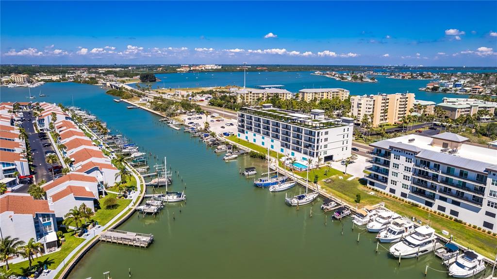 An aerial view shows a canal lined with multi-story apartment buildings and docked boats — 400 150TH AVENUE UNIT 504, MADEIRA BEACH, FL