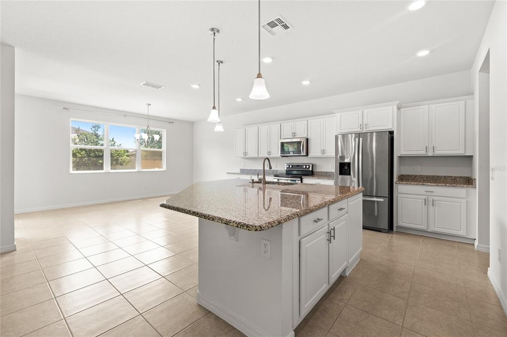 A kitchen with white cabinets, granite countertops, a center island, and tile flooring — 12135 CARSON DRIVE, ORLANDO, FL