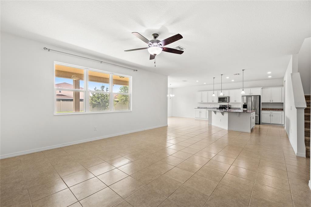 A spacious open-concept living area with tile floors, a ceiling fan, and a white kitchen — 12135 CARSON DRIVE, ORLANDO, FL
