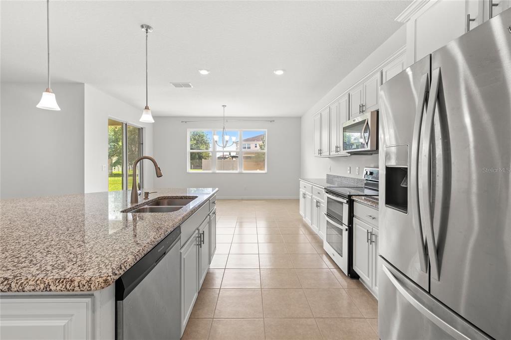 A kitchen with granite countertops, white cabinets, stainless steel appliances, and tile flooring — 12135 CARSON DRIVE, ORLANDO, FL