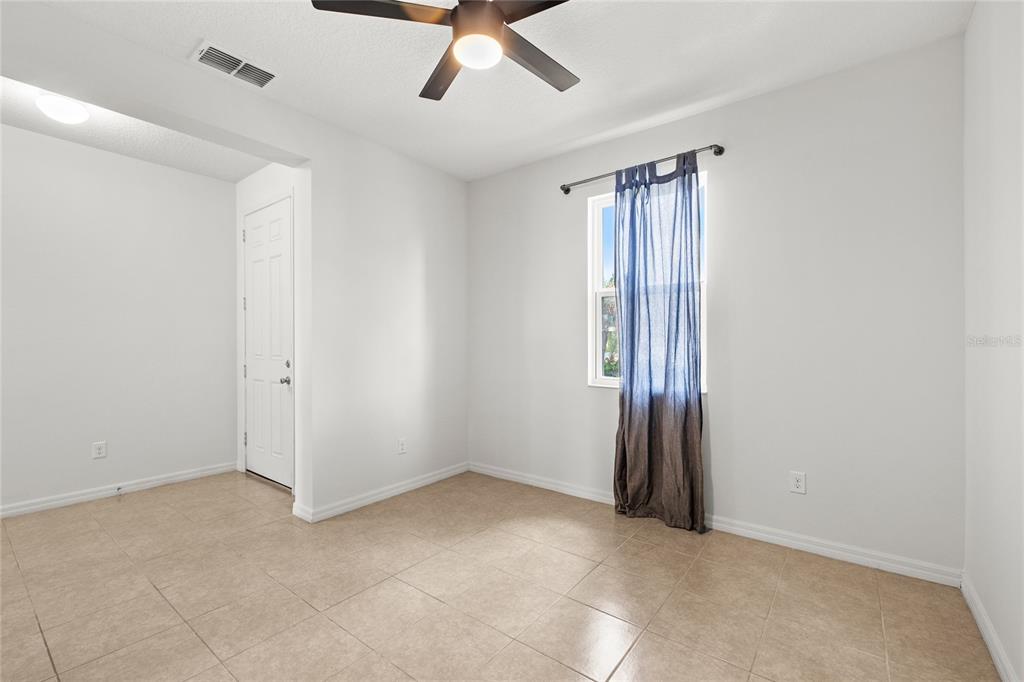 An empty room with light-colored walls, tile flooring, a ceiling fan, and a window — 12135 CARSON DRIVE, ORLANDO, FL