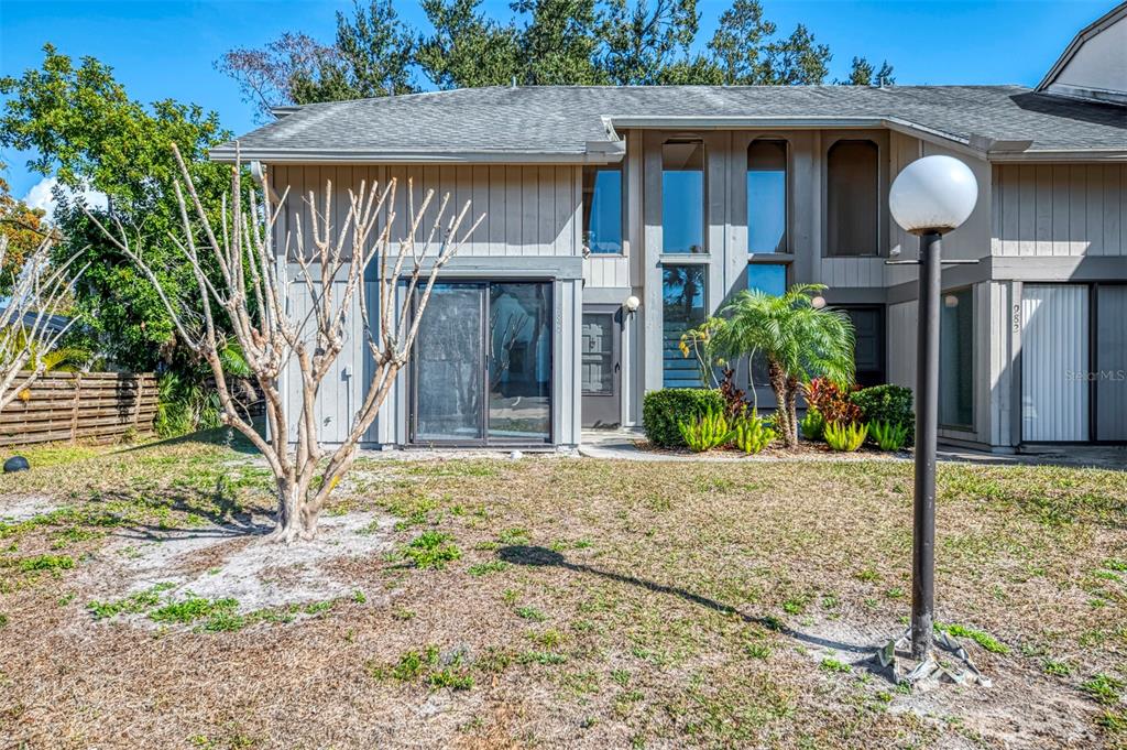 The exterior of a two-story townhouse features gray vertical siding, a sliding glass door, and landscaping — 984 N BENEVA ROAD UNIT T7, SARASOTA, FL