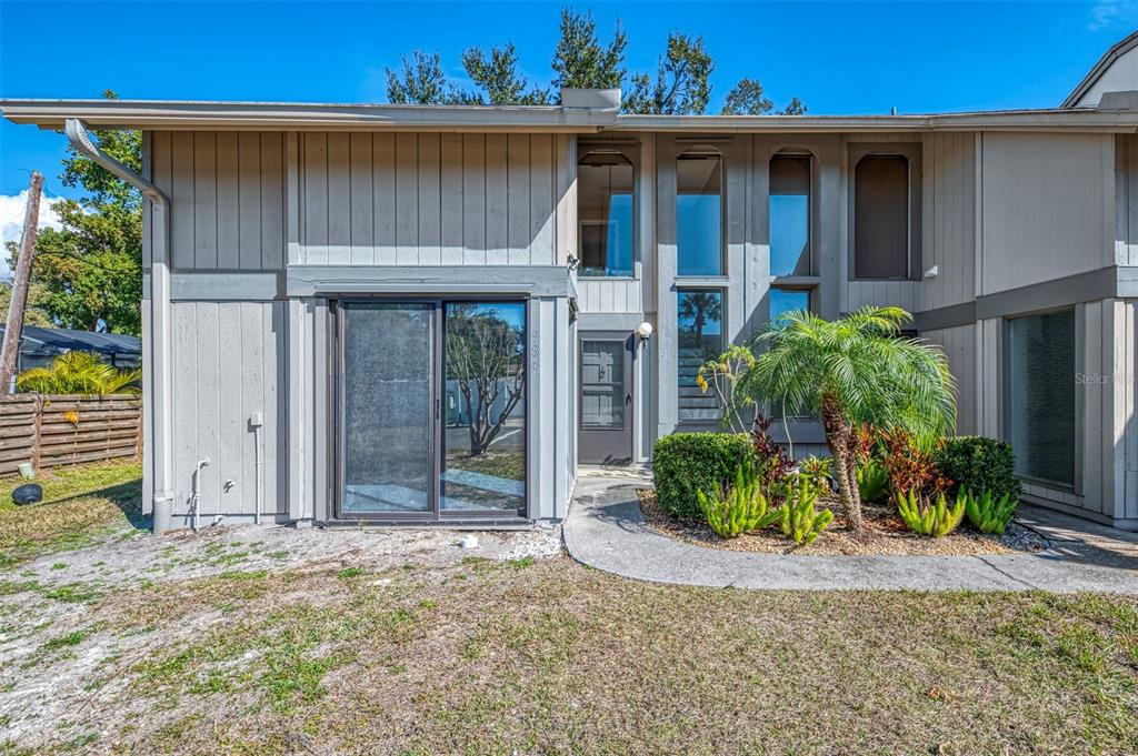 A two-story townhouse exterior with gray vertical siding, a sliding glass door, and landscaping — 984 N BENEVA ROAD UNIT T7, SARASOTA, FL