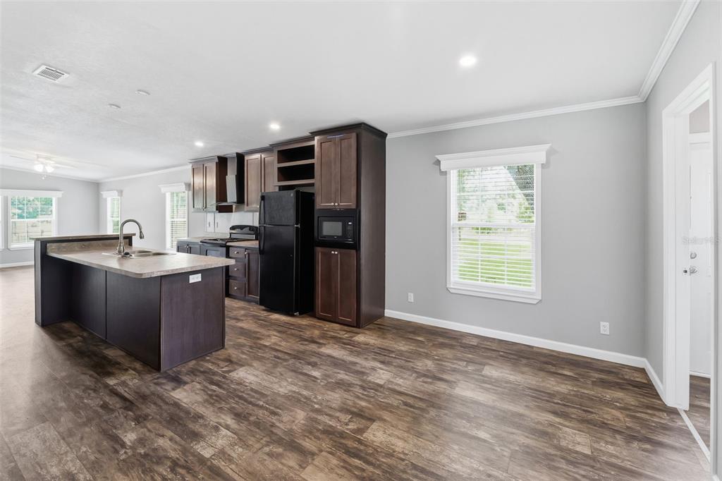A kitchen with dark wood cabinets, a black refrigerator, and a kitchen island — 7239 ROOKS DRIVE, WESLEY CHAPEL, FL