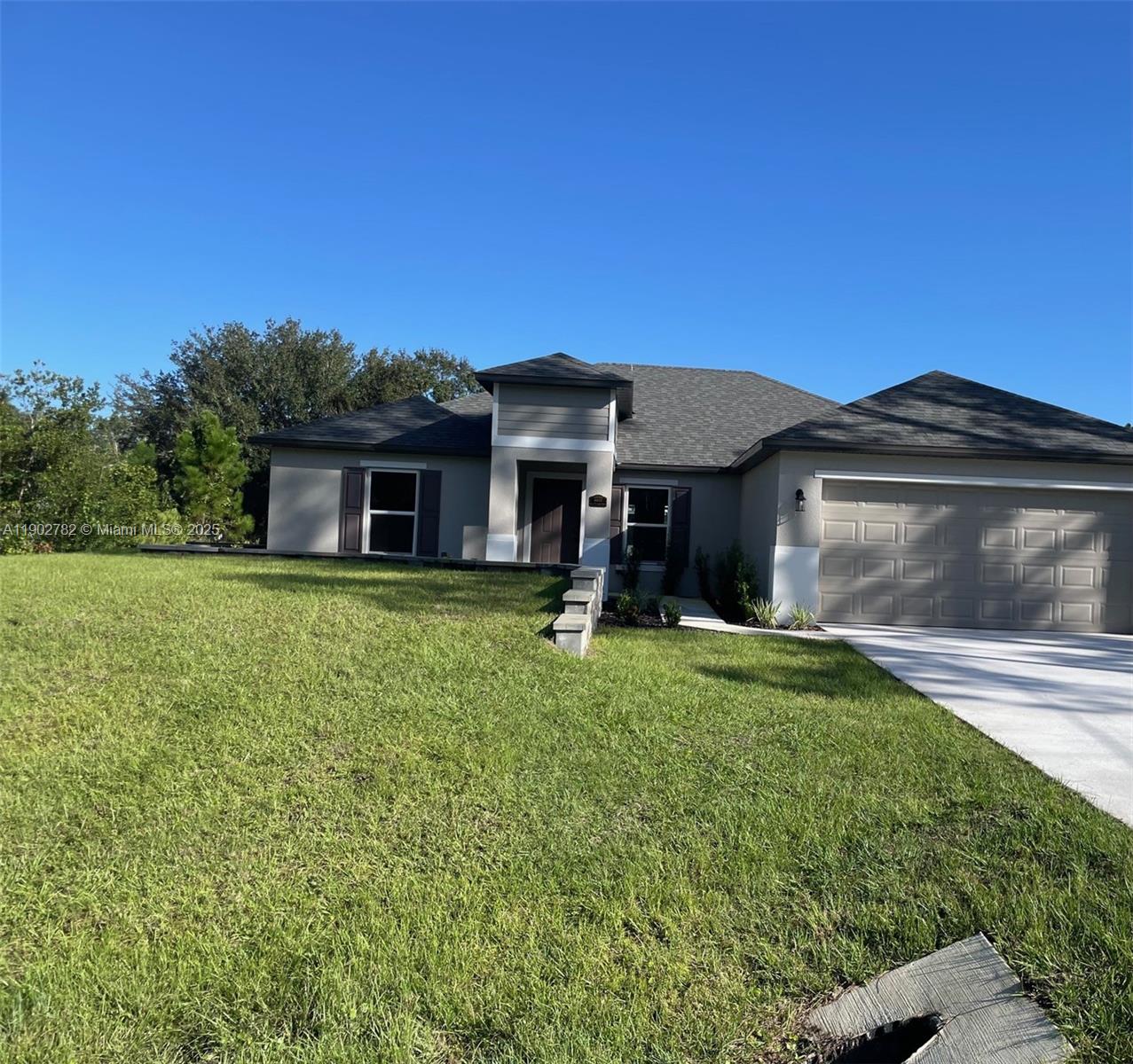 A single-story suburban house with a gray exterior, a two-car garage, and a grassy lawn — 8030 SUN N LAKES, Sebring FL 33872, SEBRING, FL