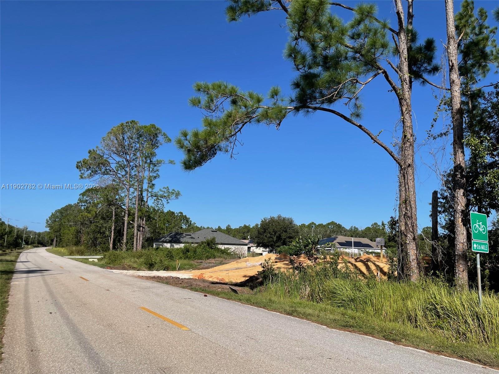 A paved road runs past a vacant lot with piles of dirt and nearby houses — 8030 SUN N LAKES, Sebring FL 33872, SEBRING, FL