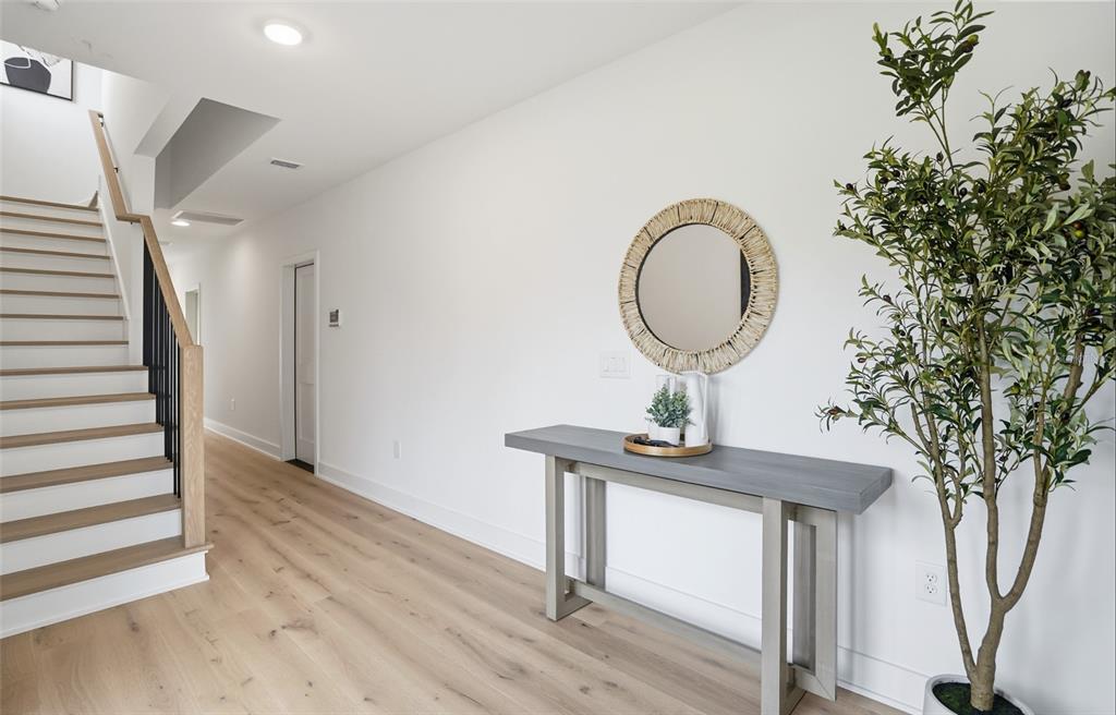 A bright entryway features light wood flooring, a staircase with black railings, and a console table — 3002 W PLATT UNIT 3, TAMPA, FL