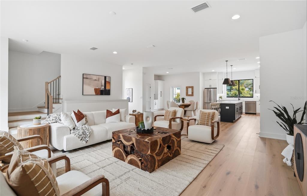 A bright, open-concept living room and kitchen featuring light wood floors and modern neutral furniture — 3002 W PLATT UNIT 3, TAMPA, FL