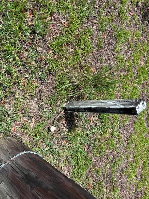 A wooden survey stake sits in the grass near a fence post — SE 16 LANE, MORRISTON, FL