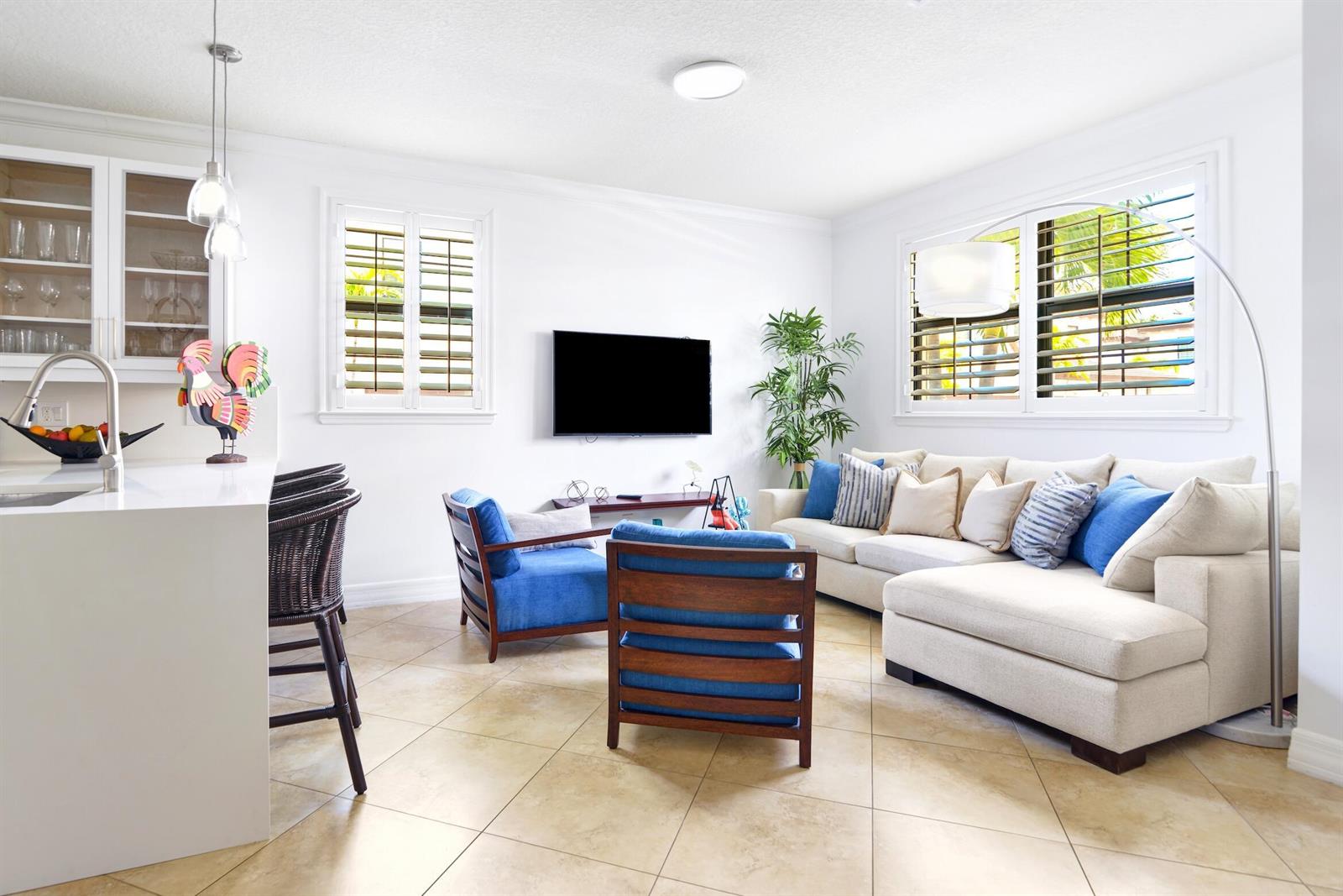A living room features a sectional sofa, two blue armchairs, and a kitchen island — 861 S Ocean Boulevard, Pompano Beach FL 33062, POMPANO BEACH, FL