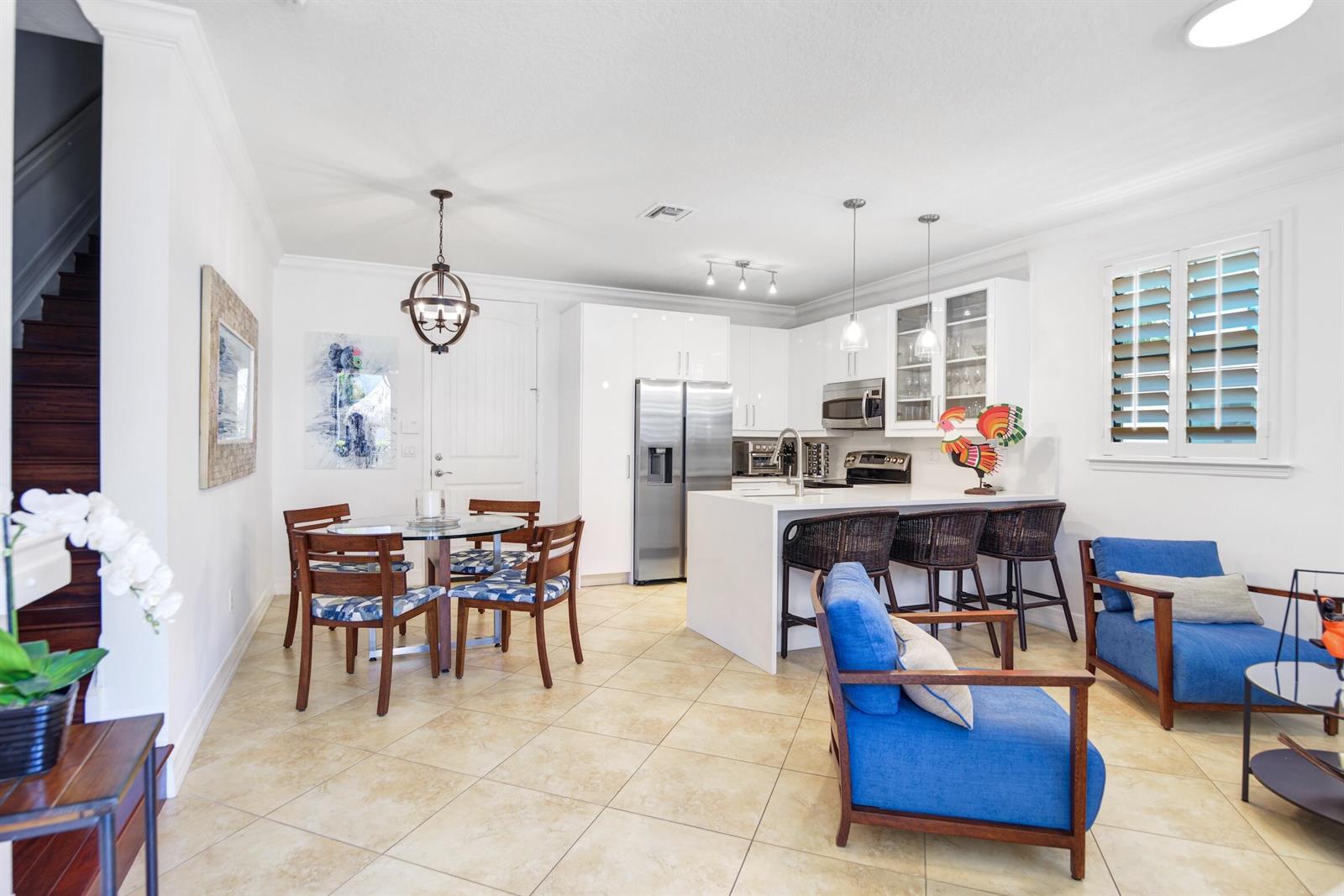 A modern kitchen with white cabinetry and a breakfast bar opens into a dining area — 861 S Ocean Boulevard, Pompano Beach FL 33062, POMPANO BEACH, FL