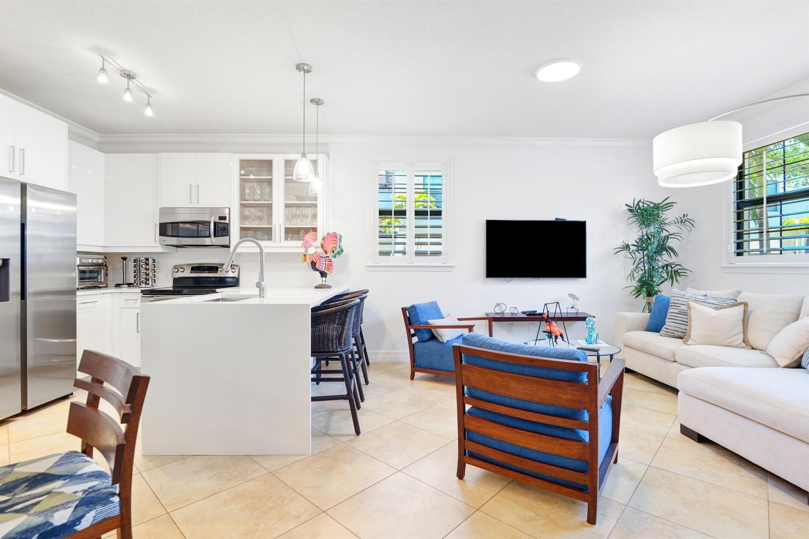 An open-concept kitchen and living area features white cabinetry, a central island, and tile flooring — 861 S Ocean Boulevard, Pompano Beach FL 33062, POMPANO BEACH, FL