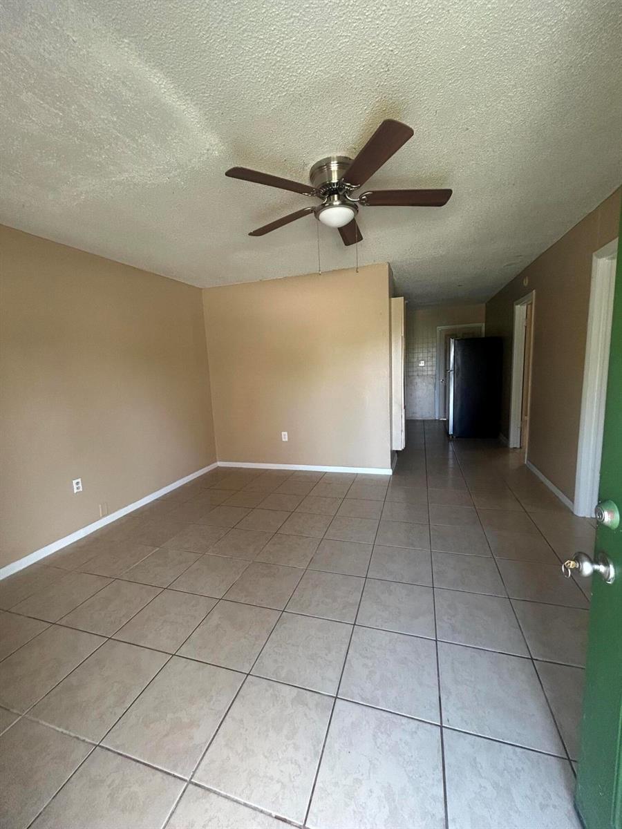 An empty room with beige walls, light-colored tile flooring, and a ceiling fan — 8657 64th Court, Vero Beach FL 32967, VERO BEACH, FL