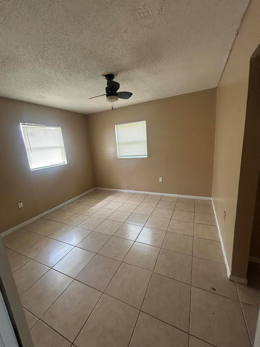 An empty room with beige walls, tile flooring, and a ceiling fan — 8657 64th Court, Vero Beach FL 32967, VERO BEACH, FL