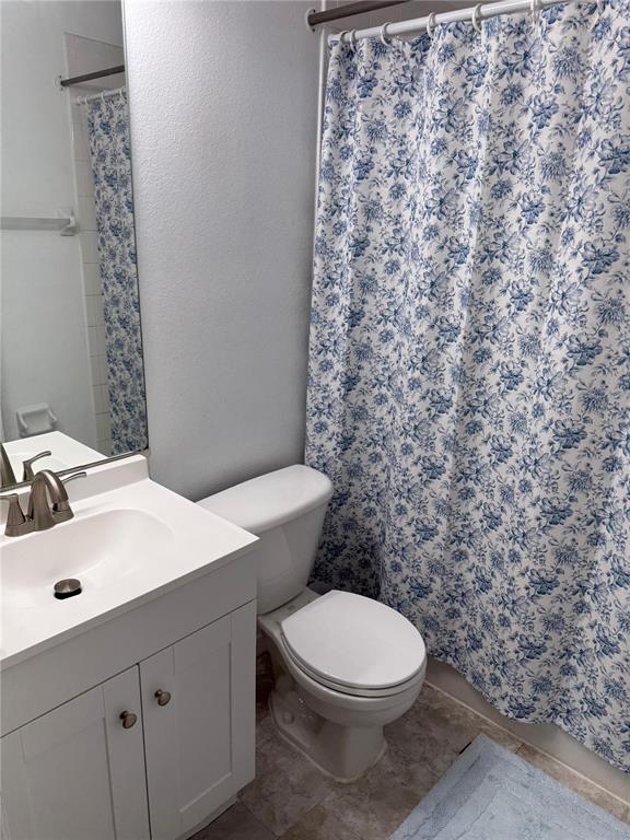A bathroom features a white vanity, a toilet, and a blue and white floral shower curtain — 2235 FLUORSHIRE DRIVE, BRANDON, FL