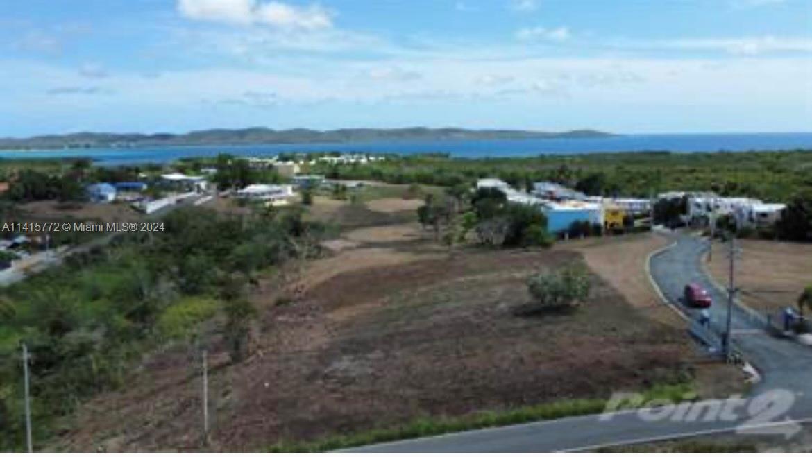 An aerial view shows a coastal landscape with a paved road, scattered buildings, and vegetation — Carretera 307 KM 7, PR 00623, PR