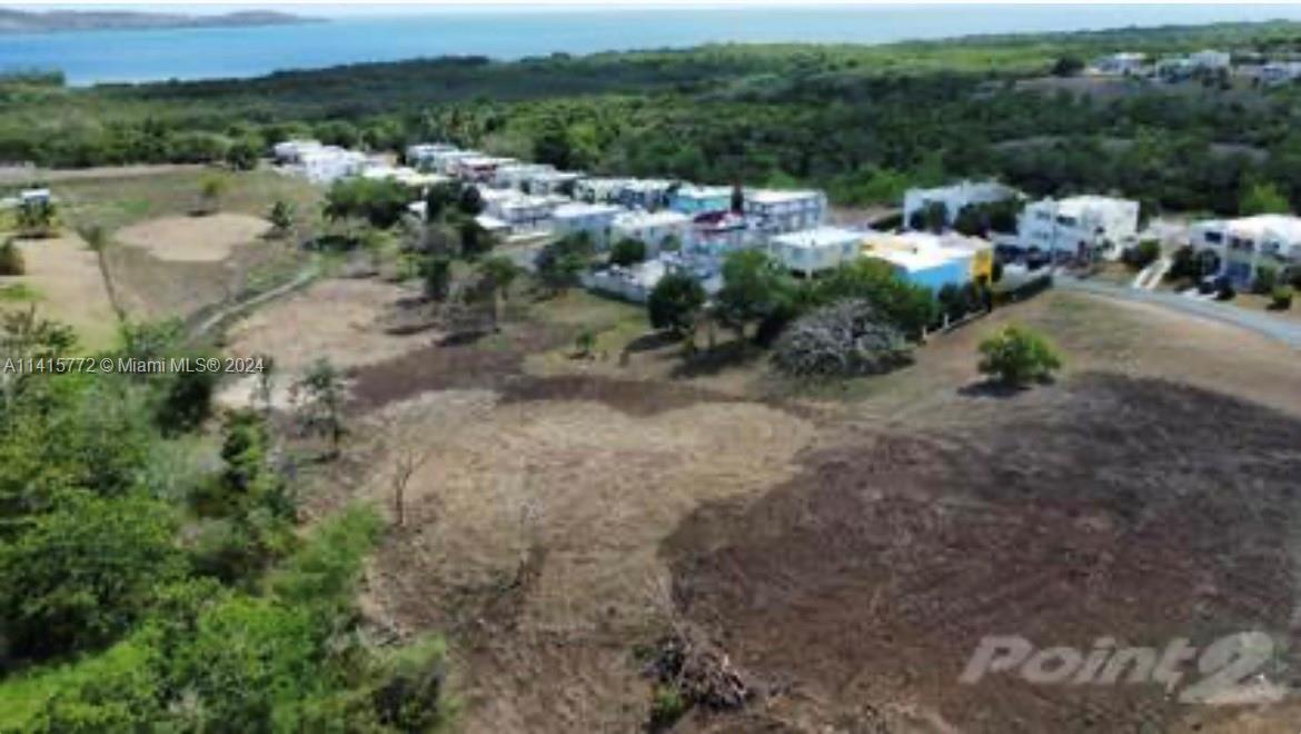 An aerial view shows a cleared, grassy lot adjacent to a residential neighborhood near water — Carretera 307 KM 7, PR 00623, PR