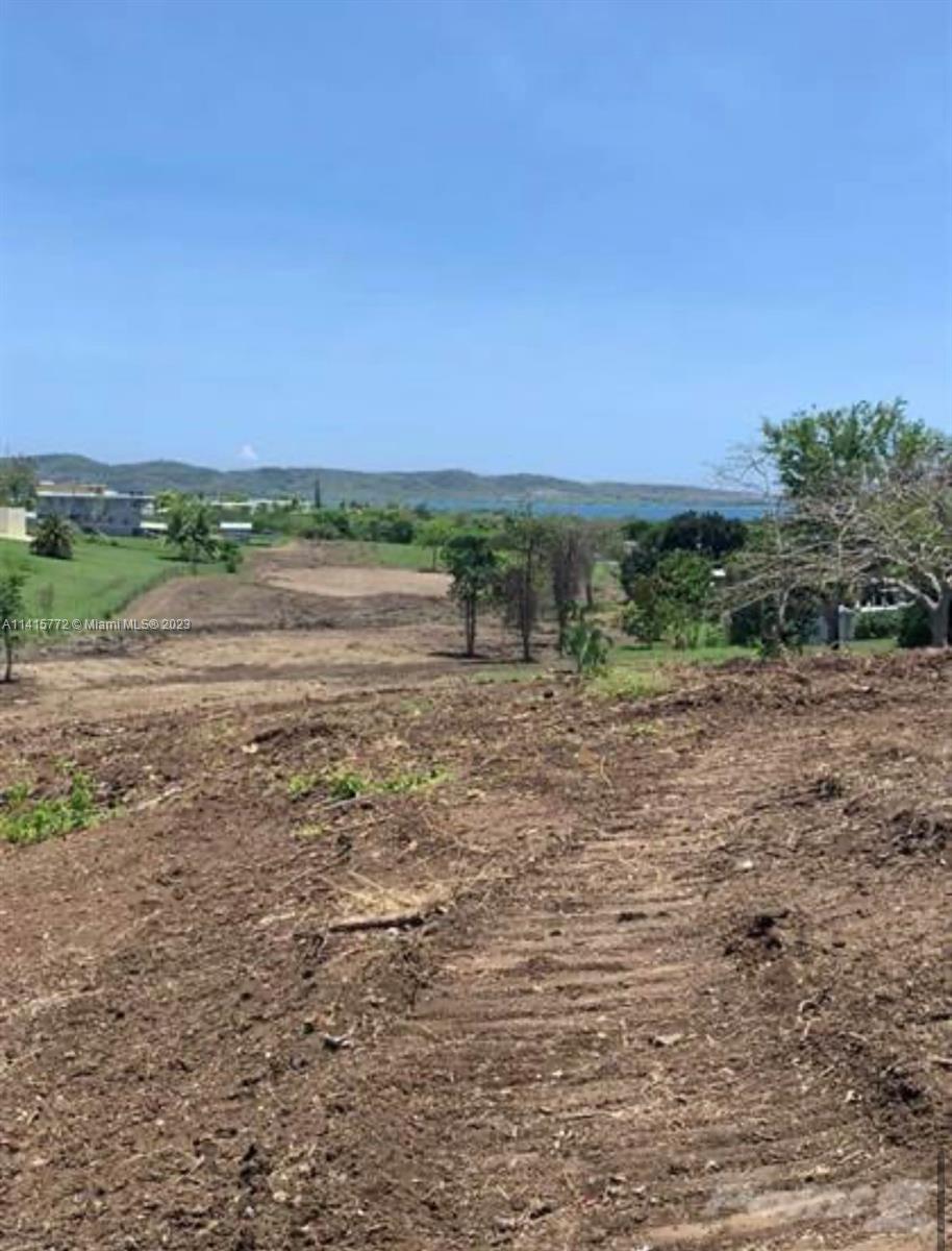 A cleared, sloping dirt lot overlooks a distant body of water and rolling hills — Carretera 307 KM 7, PR 00623, PR