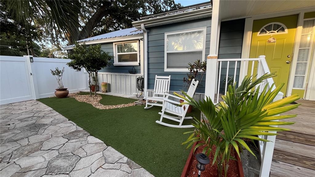A blue house exterior features a stone patio, artificial turf, and two white rocking chairs — 2301 W IDLEWILD AVENUE, TAMPA, FL