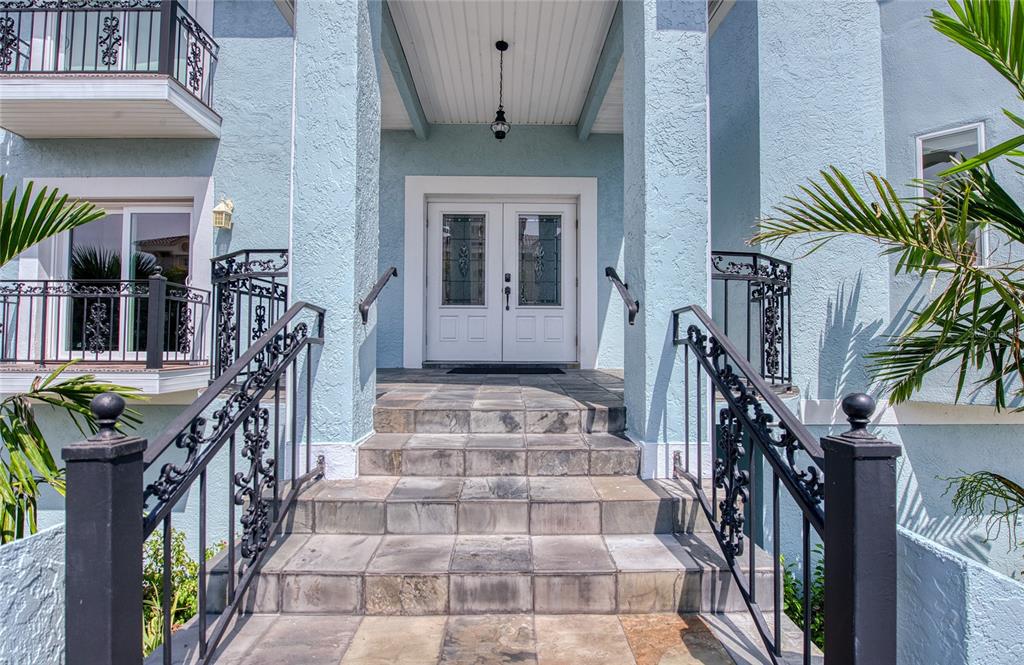 A light blue house exterior features a tiled staircase leading to a double front door — 289 8TH AVENUE N, TIERRA VERDE, FL