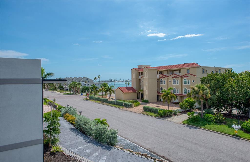 An elevated view of a coastal street with palm trees, residential buildings, and the ocean beyond — 289 8TH AVENUE N, TIERRA VERDE, FL