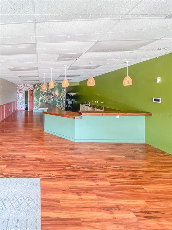 A commercial space features a wooden bar, green walls, wood-look flooring, and hanging pendant lights — 7421 MANATEE AVENUE W UNIT 7457, BRADENTON, FL