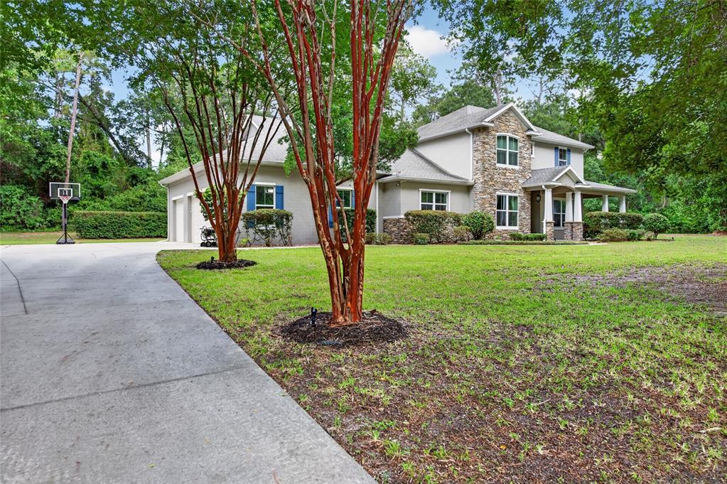 A two-story house with a stone facade, gray siding, and a concrete driveway — 1515 RAMBLING OAKS LANE, DELAND, FL